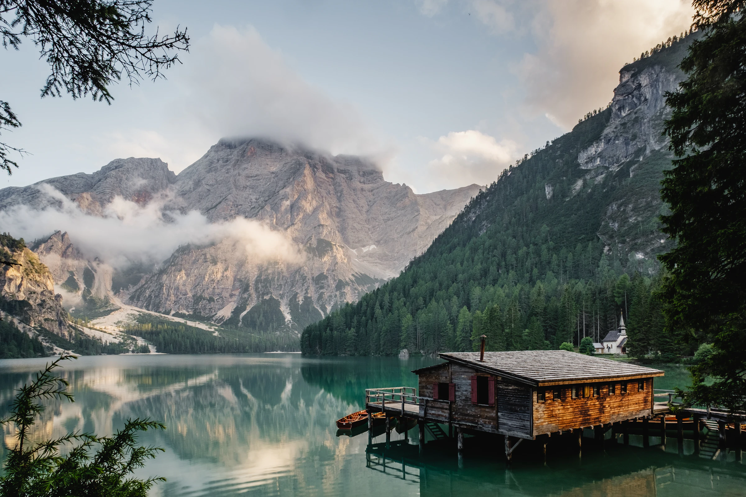 A short-term rental cabin reflected in a still mountain lake at first light, signaling premium nightly rates over volume